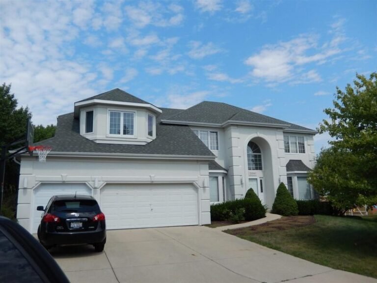 Roofing project by Adept Construction on a white two-story home