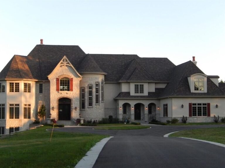 Roofing project by Adept Construction on a large stone-front home
