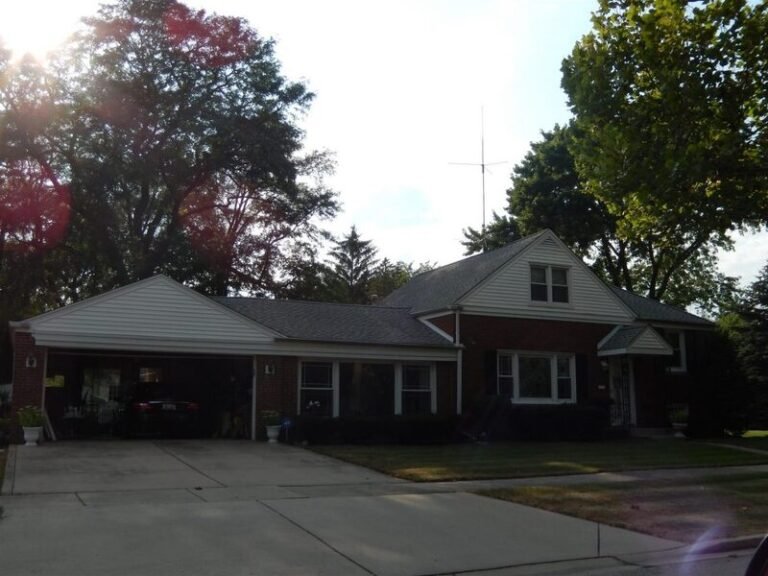 Roofing project by Adept Construction on a two-story home with gray siding and a balcony