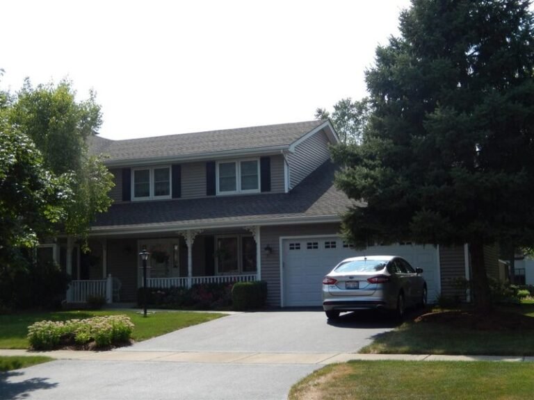 Roofing project by Adept Construction on a two-story home with a dark shingle roof and attached garage