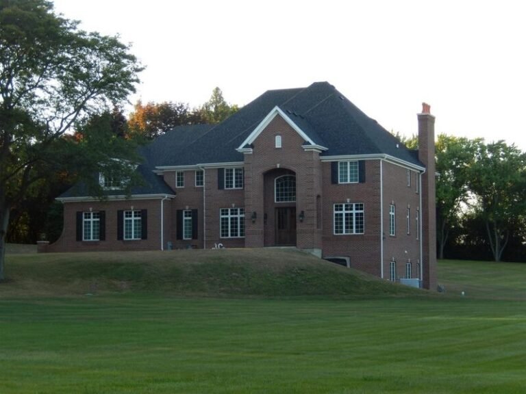 Roofing project by Adept Construction on a two-story brick home with a dark shingle roof