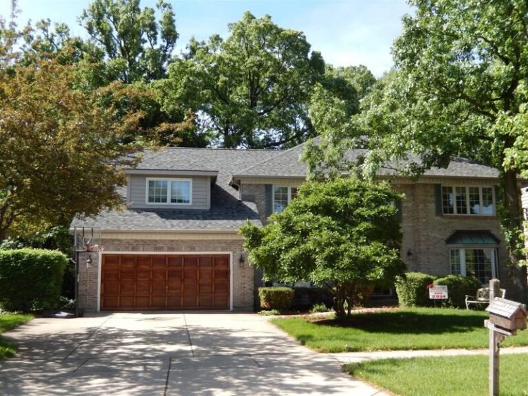Roofing project by Adept Construction on a two-story home with wood garage doors