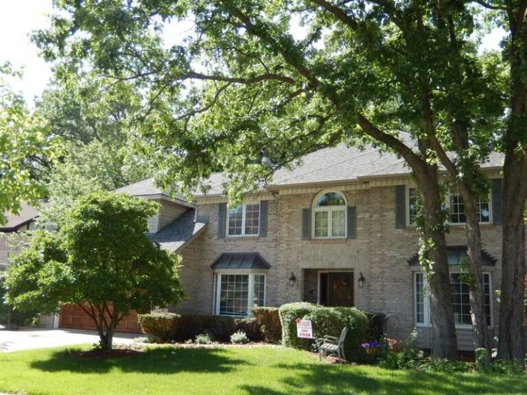Roofing project by Adept Construction on a two-story home among mature trees