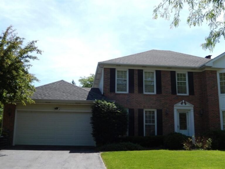 Roofing project by Adept Construction on a brick colonial home with black shutters