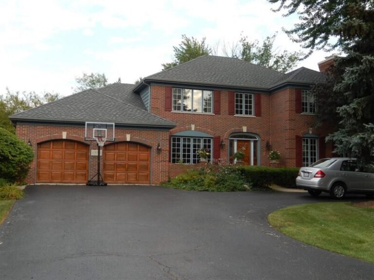Roofing project by Adept Construction on a two-story brick home with a two-car garage
