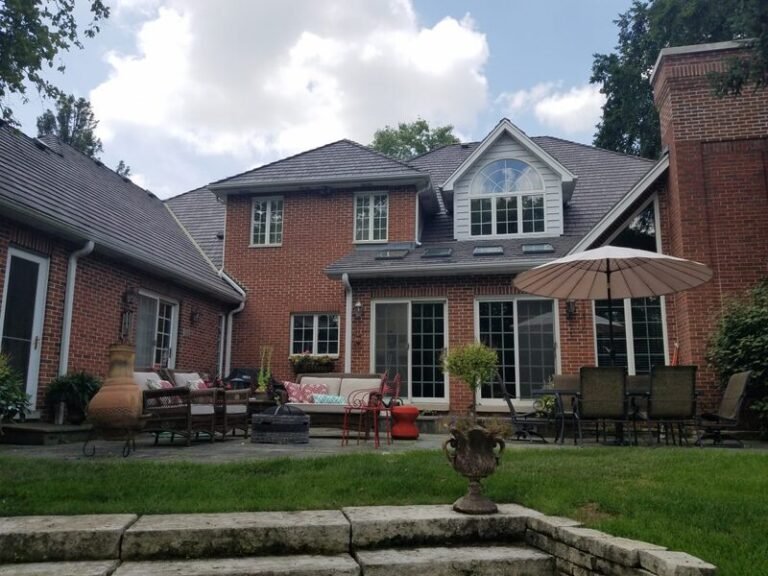 Roofing project by Adept Construction on a brick home seen from the back patio
