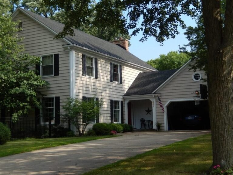 Roofing project by Adept Construction on a two-story white home with a side garage