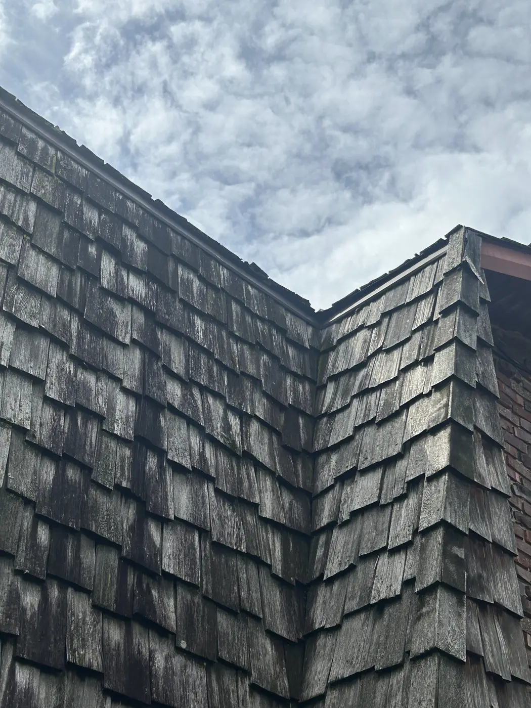 Close view of cupped and split cedar shakes at a corner in Homer Glen, IL