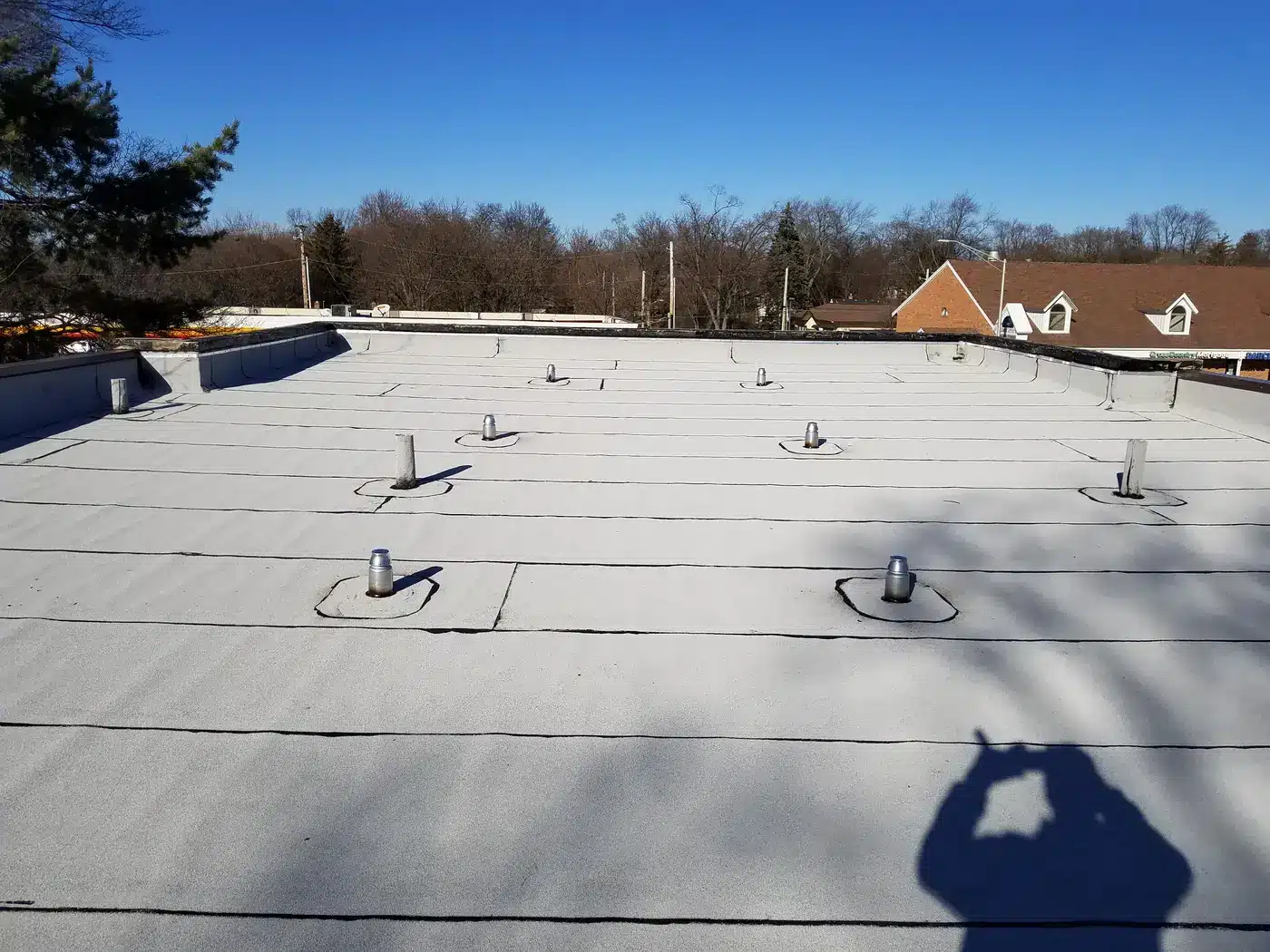 Wide view of an aging commercial flat roof with vents in Naperville, IL